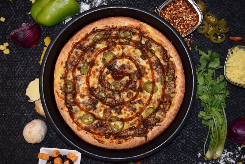 BBQ pizza with a sauce swirl and jalapeños