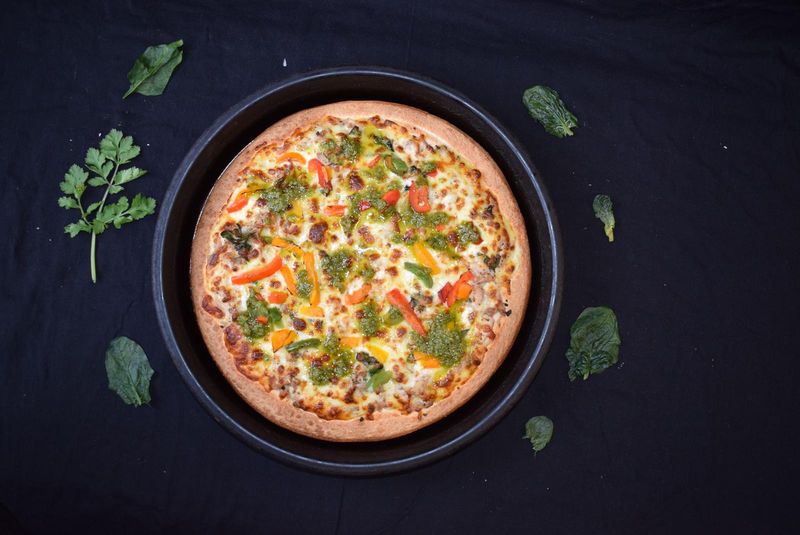 Pizza with pesto, spinach and roasted capsicum